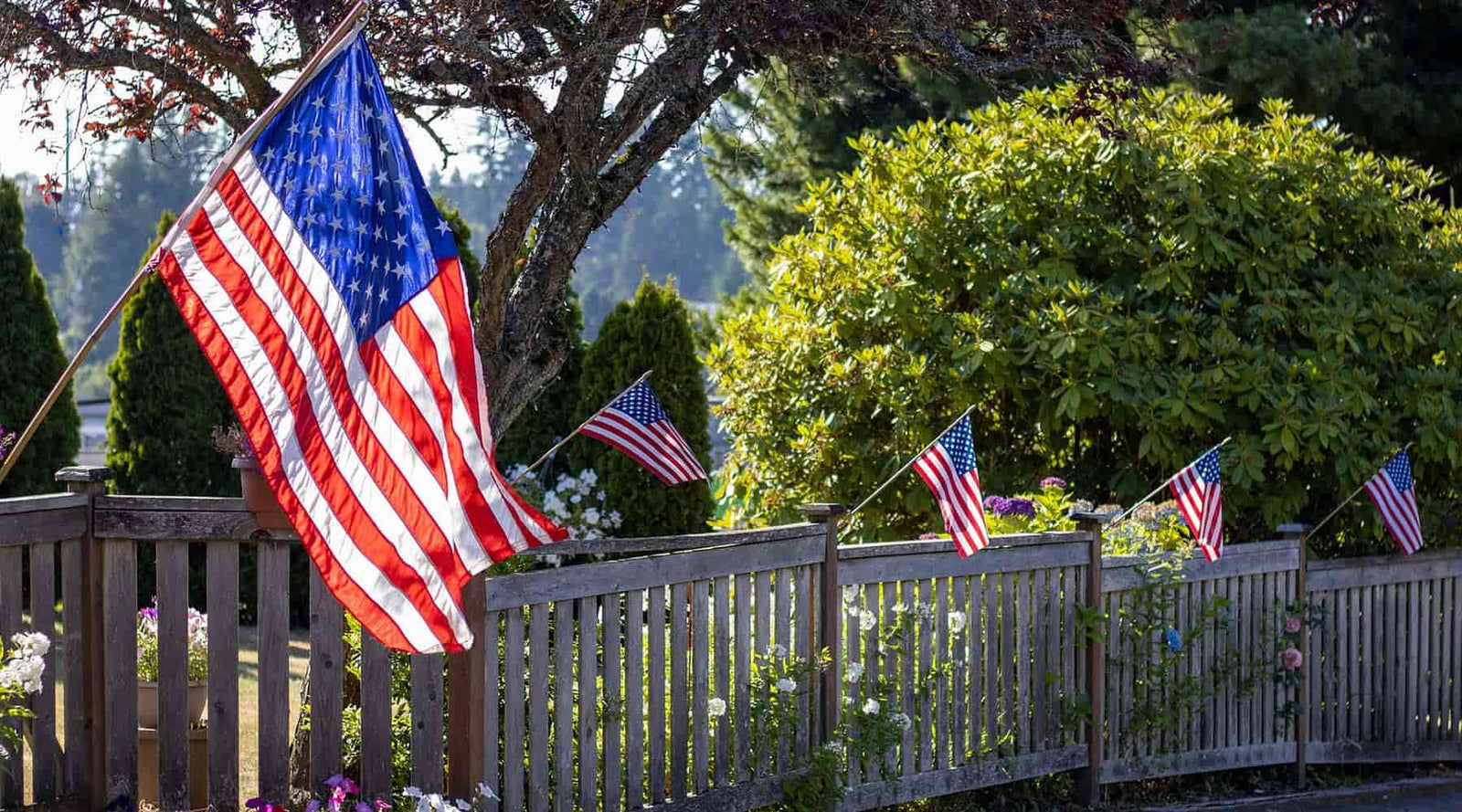 Patriotic homeschool banner showing American flags on a fence post