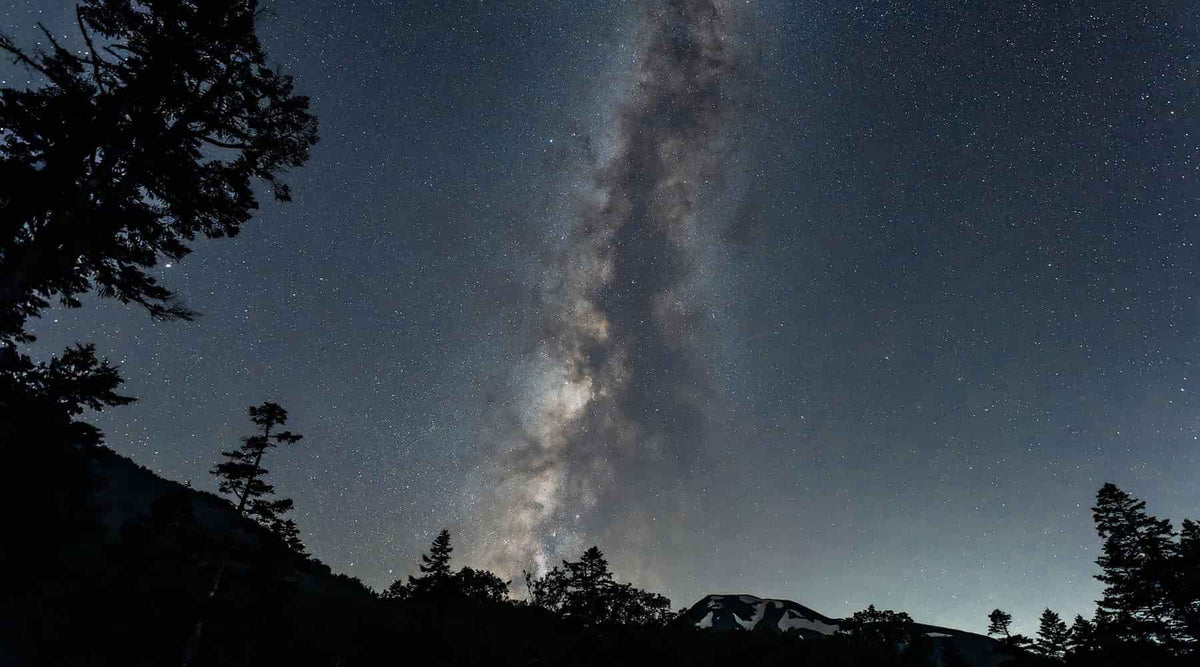 Picture of the night sky with a mountain on the horizon and milky way in the sky