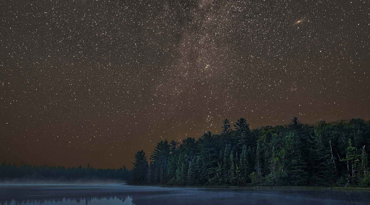 Homeschool astronomy curriculum banner of night sky over a forest and lake