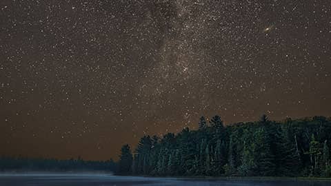 Science Shepherd Astronomy homeschool curriculum banner of night sky over lake with pine trees in the background and the Andromeda galaxy in view